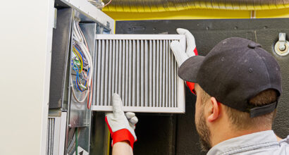 HVAC service technician changing dirty air filter in the central ventilation system. Change filter in rotary heat exchanger recuperator. Air duct ventilation system maintenance for clean air.