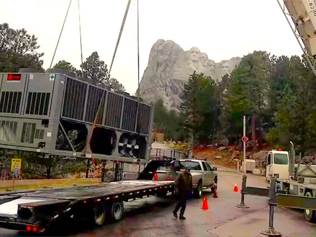 HVAC unit being lifted off truck in front of mount rushmore